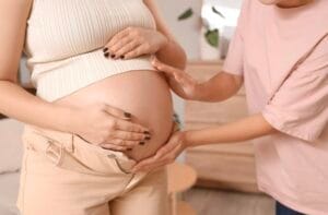 a woman is touch a pregnant woman's stomach.